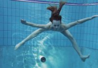 Slender girl nada y expone bajo el agua en la piscina